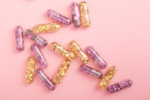 pile of sparkling drug capsules scattered on pink surface
